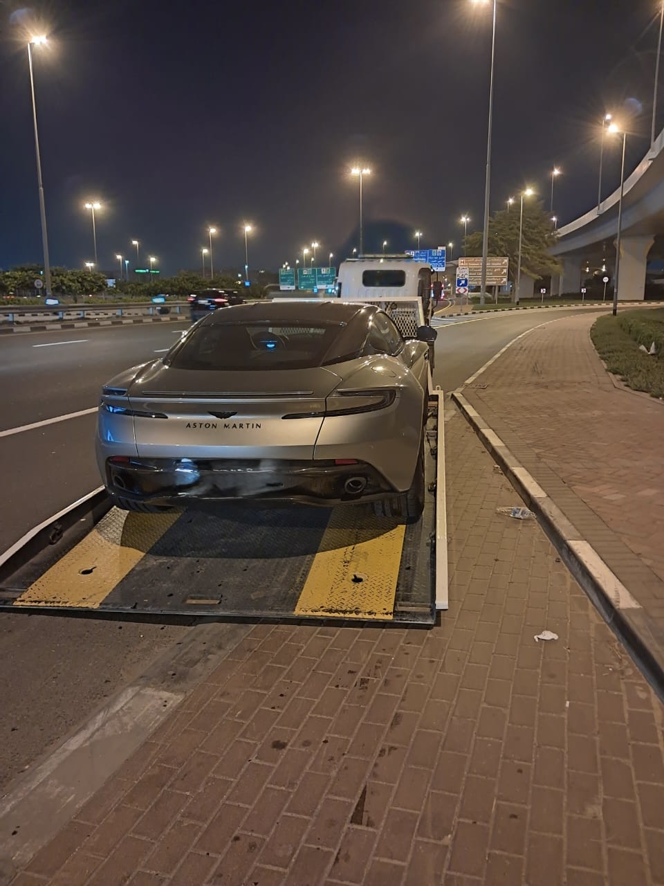 Aston Martin DB11 recovered on a flatbed at night in Dubai